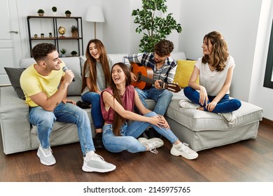 Group of young friends on party playing classical guitar and singing song at home. - Powered by Shutterstock