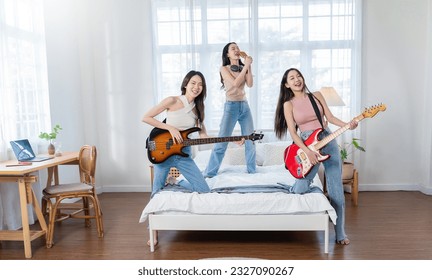 Group of young friends on party smile happy playing classical rock guitar on bed room home. photo serenade gathering best modern friends hang out play guitar for hobby leisure activities social med - Powered by Shutterstock