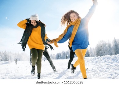 A Group Of Young Friends On A Walk Outdoors In Snow In Winter Forest, Running.