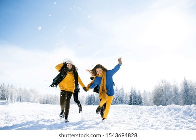 Group Of Young Friends On A Walk Outdoors In Snow In Winter Forest, Having Fun.
