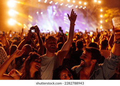 Group of young friends partying and celebrating at summer music festival. They are dancing in front of stage. Wearing casual clothing - Powered by Shutterstock