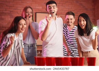 Group of young friends playing beer pong at party - Powered by Shutterstock