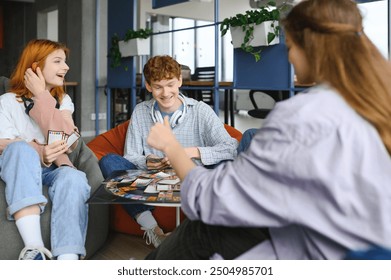 group of young friends playing board games together while sitting around table. - Powered by Shutterstock