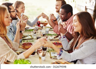 Group Of Young Friends Praying At Thanksgiving Table