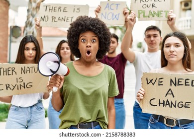 Group Of Young Friends Protesting And Giving Slogans At The Street Scared And Amazed With Open Mouth For Surprise, Disbelief Face 