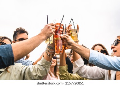 Group of young friends raises plastic glasses with spritz and fruit cocktails for a celebrate toast against a white background sky - concept of happy people having fun outdoors drinking and clinking - Shutterstock ID 2157720851