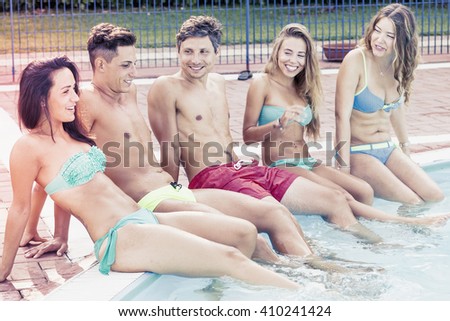 group of young friends sitting by the pool