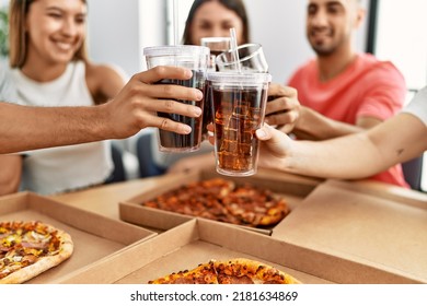 Group of young friends smiling happy eating italian pizza and toasting with cola beverage at home.