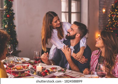 Group of young friends spending Christmas day togehter at home, having fun over Christmas dinner; couple in love having Christmas dinner for friends at home - Powered by Shutterstock