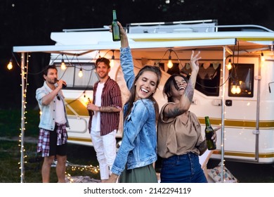 Group of young friends spending time on the camping side and drinking beer in the evening - Powered by Shutterstock