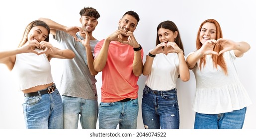 Group Of Young Friends Standing Together Over Isolated Background Smiling In Love Doing Heart Symbol Shape With Hands. Romantic Concept. 