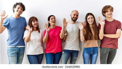 Group Of Young Friends Standing Together Over Isolated Background Waiving Saying Hello Happy And Smiling, Friendly Welcome Gesture 