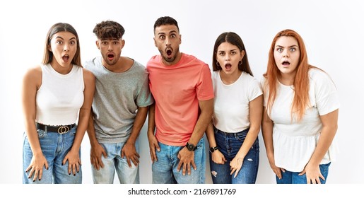 Group of young friends standing together over isolated background afraid and shocked with surprise and amazed expression, fear and excited face. 