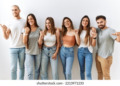 Group Of Young Friends Standing Together Over Isolated Background Pointing To The Back Behind With Hand And Thumbs Up, Smiling Confident 