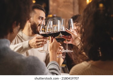 Group of young friends toasting with red wine for celebration at restaurant - young adults clinking raising wineglasses - people friendship and lifestyle concept - Powered by Shutterstock