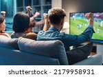 Group of young friends watching a football match on TV together and cheering for their team