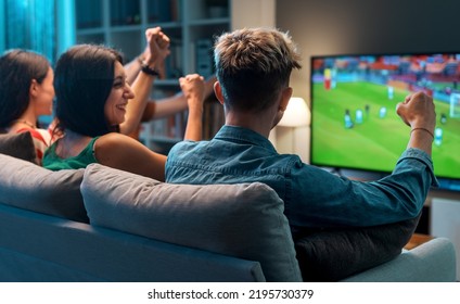 Group of young friends watching a football match on TV together and cheering for their team - Powered by Shutterstock