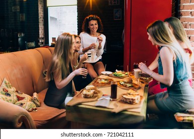 Group Of Young Girlfriends Having Lunch In Fast Food Restaurant Eating Craft Hamburgers