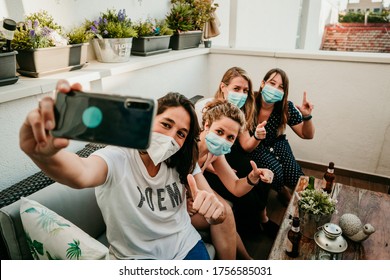 Group of young girlfriends meeting after the quarantine caused by the covid19. Taking precaution with surgical masks and taking photos together with a smartphone.