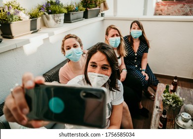 Group Of Young Girlfriends Meeting After The Quarantine Caused By The Covid19. Taking Precaution With Surgical Masks And Taking Photos Together With A Smartphone.