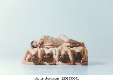 Group of young girls, ballet dancers performing, posing isolated over grey studio background. Sleeping on girls back. Concept of art, beauty, aspiration, creativity, classic dance style, elegance - Powered by Shutterstock