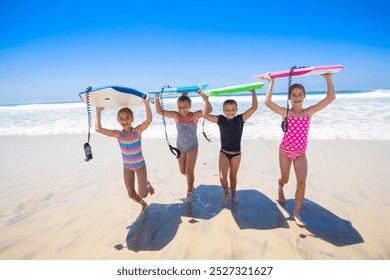 Group of young girls carrying their boogie boards at the beach after playing in the scenic Pacific Ocean. Fun summer lifestyle concept photo	 - Powered by Shutterstock