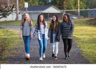 Group of young girls holding hands and laughing while walking on