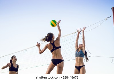 Group of young girls playing beach volleyball during sunset or sunrise - Powered by Shutterstock