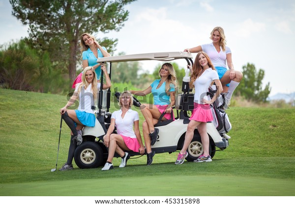 Group of young golf caddies posing on a golf\
cart on golf course with copy\
space.