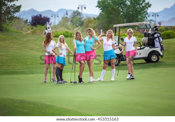 Group of young golf caddies in a row posing on a\
golf course.