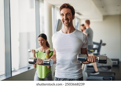 Group of young happy fit people doing exercises together in modern fitness gym - Powered by Shutterstock