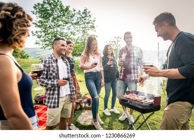 Gruppe junger glücklicher Freunde, die im Freien pic-nic sind - Menschen, die Spaß haben und feiern, während sie auf dem Lande Grillen-Grill-Party machen