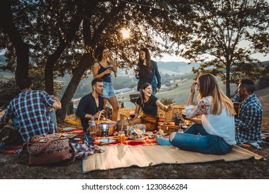 Group of young happy friends having pic-nic outdoors - People having fun and celebrating while grilling ata barbacue party in a countryside - Powered by Shutterstock