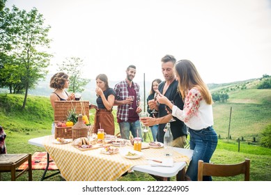 Group of young happy friends having pic-nic outdoors - People having fun and celebrating while grilling ata barbacue party in a countryside