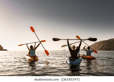 Grupo de jóvenes y felices kayakers se están divirtiendo en poses ganadoras al atardecer de la bahía del mar