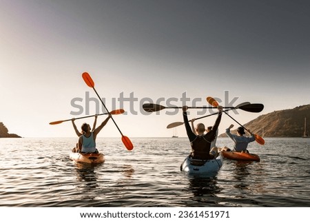Group of young happy kayakers are having fun in winner poses at sunset sea bay