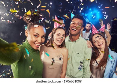 Group Of Young Happy Multiracial People Wearing Birthday Hats Making A Selfie On Mobile Phone, Confetti Falling In The Air