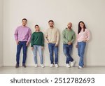 Group of young happy smiling friends students or colleagues wearing casual clothes standing together in a row and posing isolated on white background and looking positively at camera.