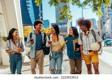 A group of young happy students are walking together in the city on their way to school. They have their backpacks, books and notebooks in their hands. - Powered by Shutterstock