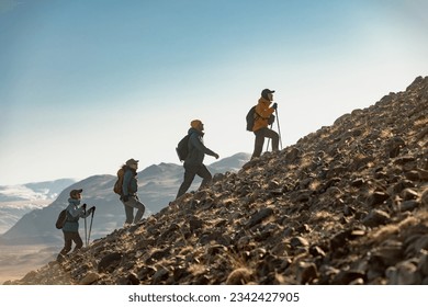 Group of young hikers walks with backpacks uphill together. Active tourism concept - Powered by Shutterstock