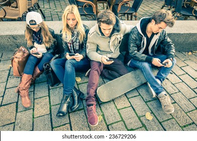 Group of young hipster friends using smart phone with disinterest on each other - Modern situation of technology addiction in alienated lifestyle - Internet wifi connection on vintage filtered look