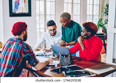 Group Of Young Hipster IT Professionals Discussing Report Information During Co Brainstorming In Modern Apartment With Wifi Connection For Developing, Diverse Students Preparing To Program Test