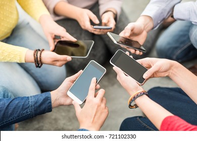 Group Of Young Hipsters Holding Phone In Hands. Friends Having Fun Together With Smartphones.