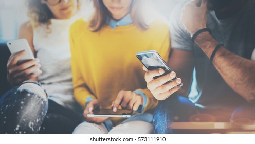 Group Of Young Hipsters Sitting On Sofa Holding En Hands And Using Electronic Gadgets.Coworking Teamwork Concept.Horizontal,blurred Background