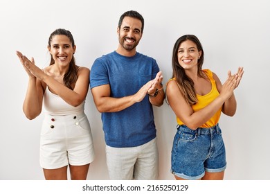 Group Of Young Hispanic People Standing Over Isolated Background Clapping And Applauding Happy And Joyful, Smiling Proud Hands Together 