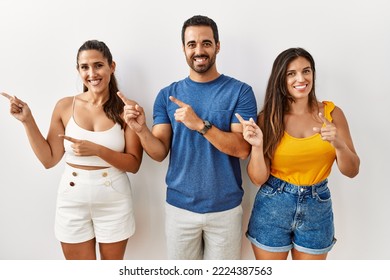 Group Of Young Hispanic People Standing Over Isolated Background Smiling And Looking At The Camera Pointing With Two Hands And Fingers To The Side. 