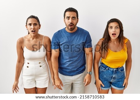 Group of young hispanic people standing over isolated background afraid and shocked with surprise and amazed expression, fear and excited face. 