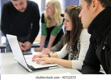 Group Of Young International Students Working On A Laptop And Discussing