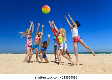 Group Of Young Joyful Girls Playing Volleyball On The Beach