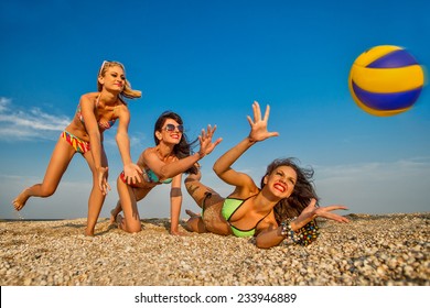 Group Of Young Joyful Girls Playing Volleyball On The Beach